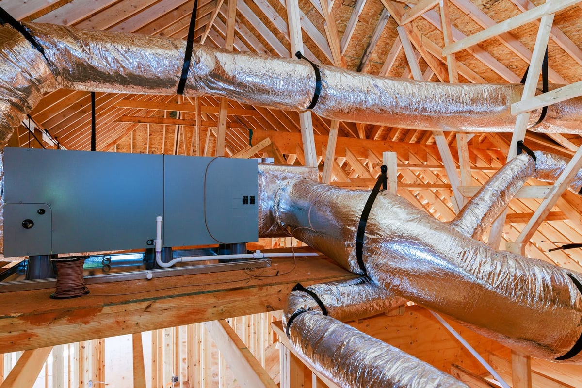 Workers setting up ductwork for heating and cooling in residential building under construction